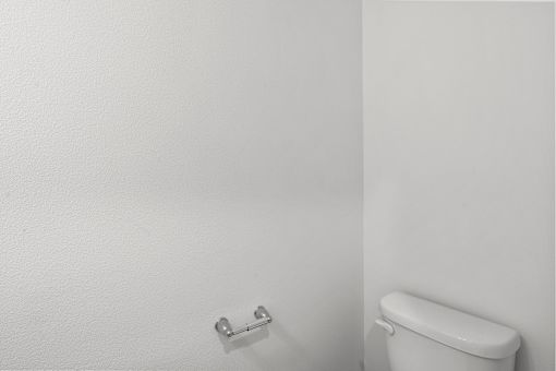 A white toilet in a bathroom with a white wall.