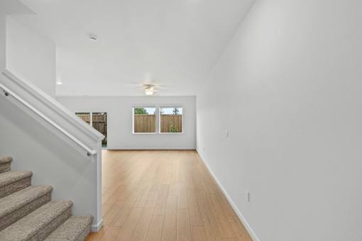 A long hallway with a staircase on the left and a window on the right.