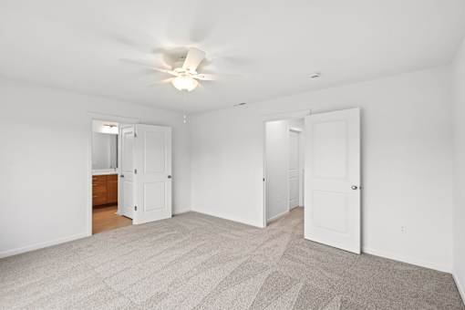 A spacious room with a ceiling fan and carpeted floor.