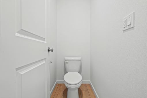 A white toilet in a small bathroom with a door on the left.
