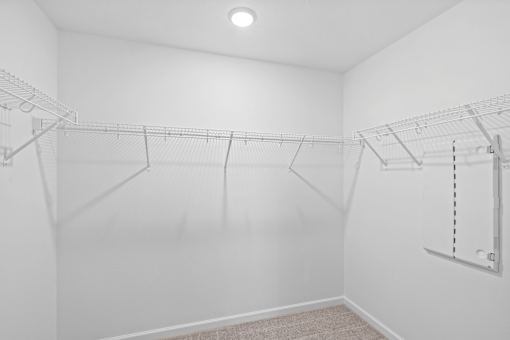 Empty white closet with shelves and a light on the ceiling.