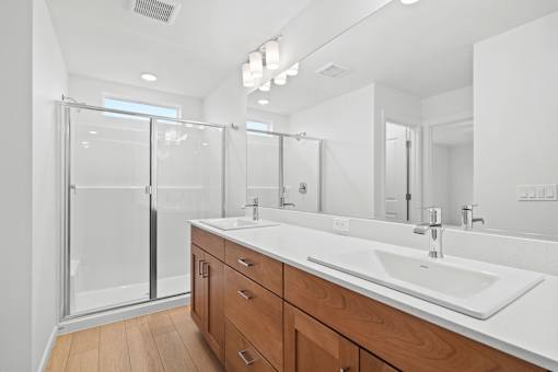 A modern bathroom with a white sink and wooden cabinets.