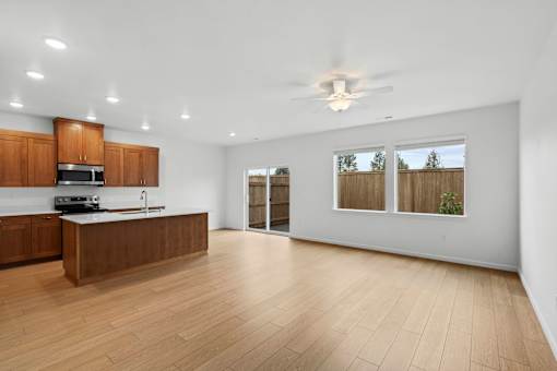 A spacious kitchen with wooden floors and a ceiling fan.