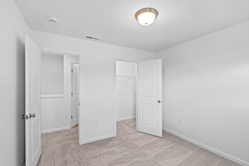 A white room with a carpeted floor and three doors.