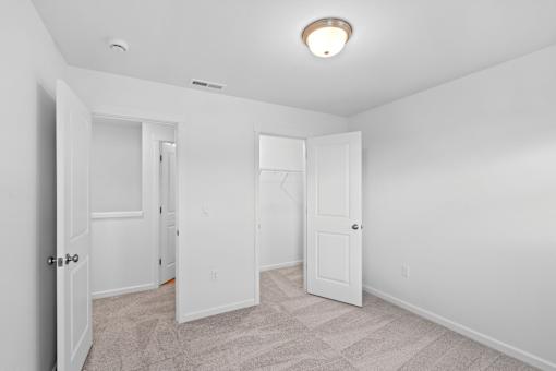 A white room with a carpeted floor and three doors.