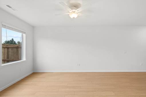 Empty room with a ceiling fan and a window.