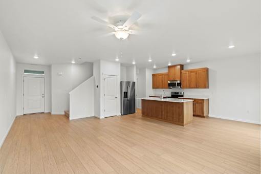A spacious room with a kitchen area and wooden flooring.