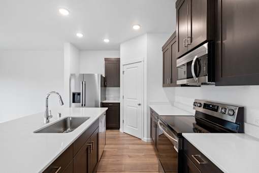 A modern kitchen with dark brown cabinets and white countertops.