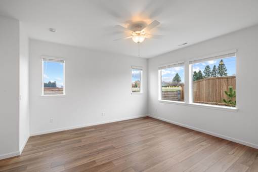 A room with a ceiling fan and three windows.