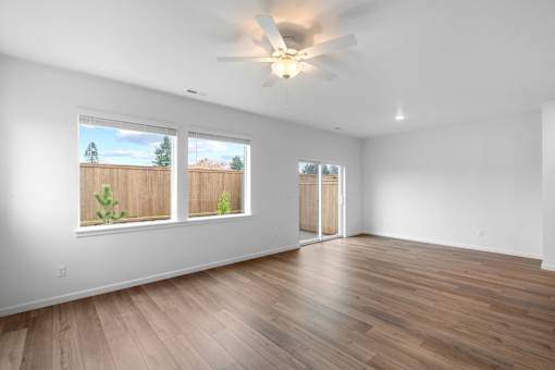 A room with a ceiling fan and wooden flooring.