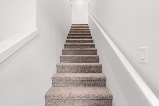 A staircase with a carpeted runner and white walls.