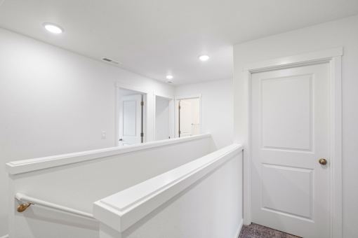 A white bathroom with a door and a mirror.