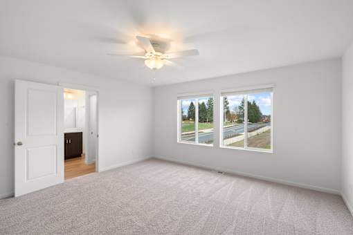 A room with a carpeted floor and a window showing a street view.