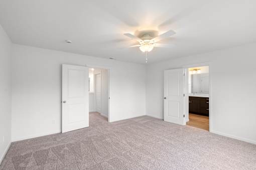 A room with a ceiling fan and carpeted floor.