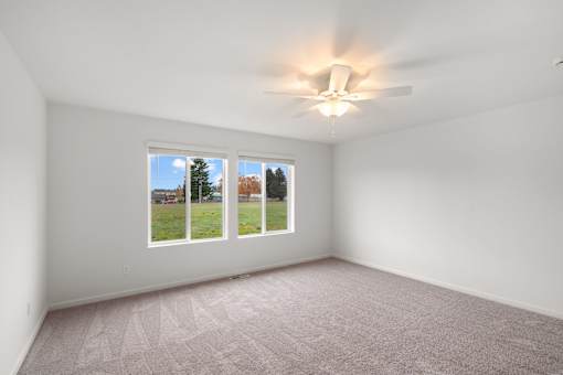 A room with a carpeted floor and a window showing a view of a house and trees.