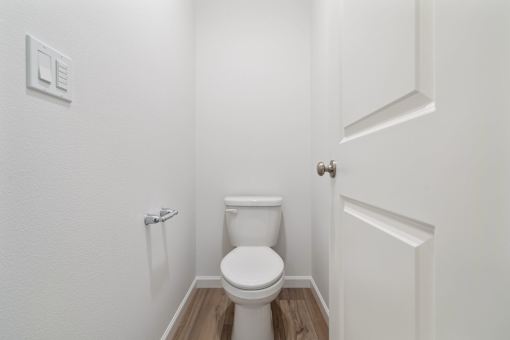 A white toilet in a small bathroom with a door to the right.