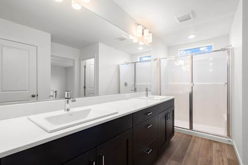 A bathroom with a white sink and black drawers.