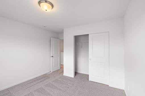 A room with a carpeted floor and two white doors.
