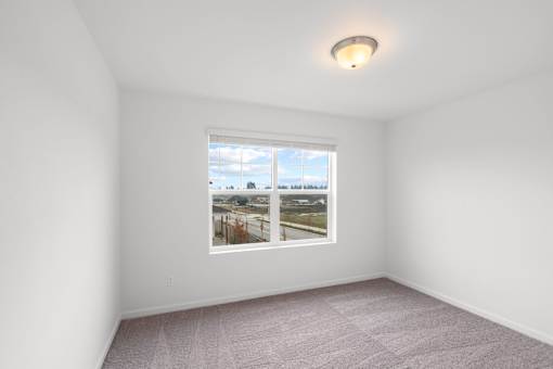A room with a window showing a view of a street with houses.