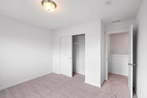 A white room with a carpeted floor and two open doors.