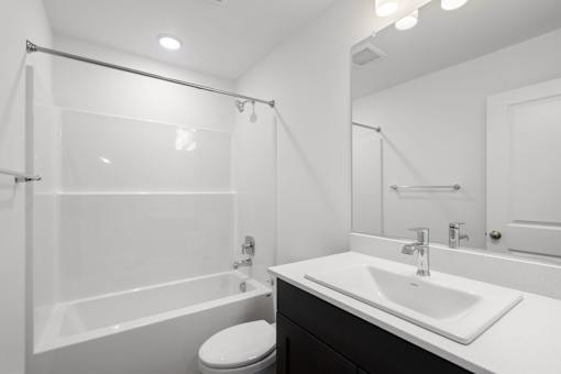 A white bathroom with a toilet, sink, and shower.