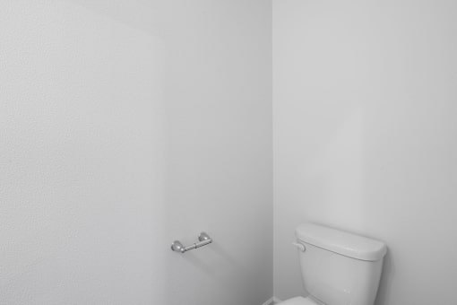 A white toilet in a bathroom with a white wall.