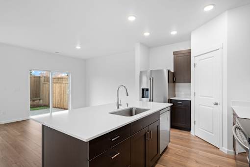 A modern kitchen with dark brown cabinets and white countertops.