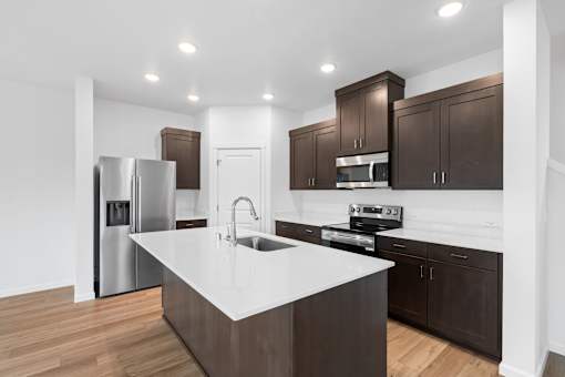 A modern kitchen with dark brown cabinets and a white island.