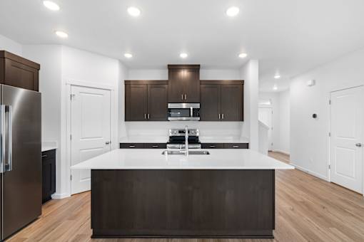 A modern kitchen with dark brown cabinets and a white island.