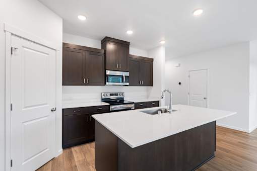 A modern kitchen with dark brown cabinets and white countertops.