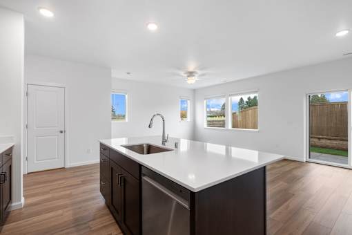 A kitchen with a white countertop and wooden floors.