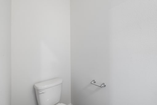 A white toilet sits next to a white wall.
