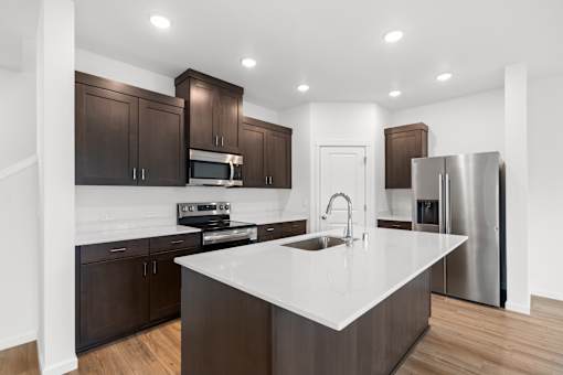 A modern kitchen with dark brown cabinets and a white countertop.