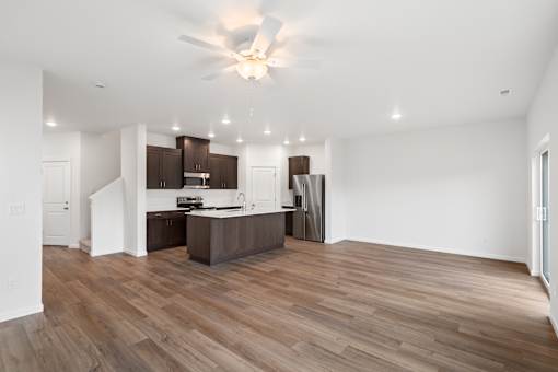 A kitchen with wooden floors and a ceiling fan.