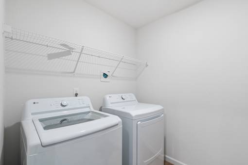 A white dryer and washing machine in a small laundry room.