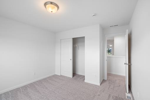 A spacious room with a carpeted floor and white walls.