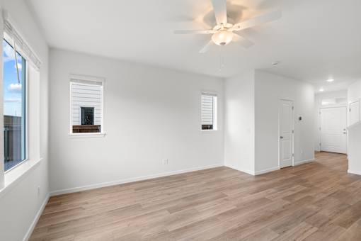 A room with a ceiling fan and wooden flooring.