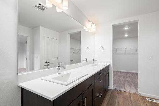 A bathroom with a white sink and brown drawers.
