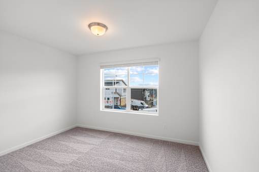 A white room with a window showing a view of a building and a blue sky.