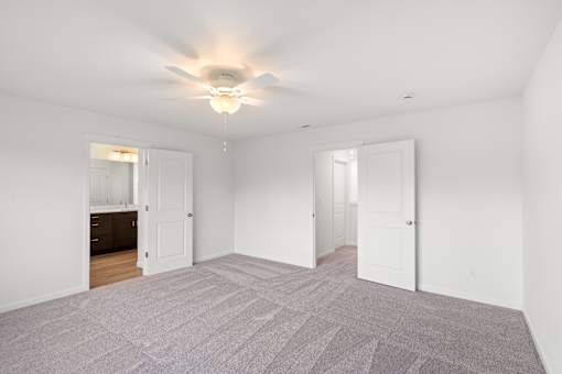 A room with a carpeted floor and a ceiling fan.