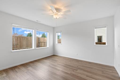 A room with a ceiling fan and wooden flooring.