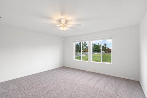 A room with a carpeted floor and a window showing a view of trees.