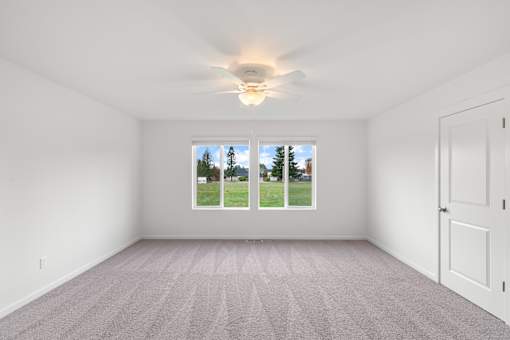 A room with a carpeted floor and a ceiling fan.