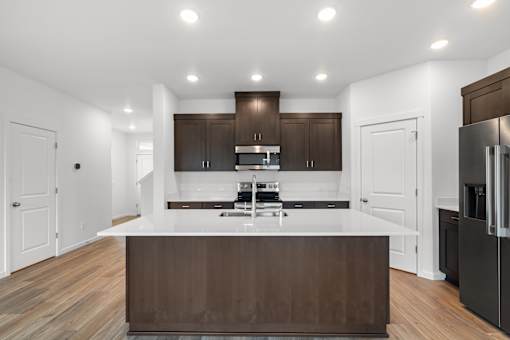 A modern kitchen with dark brown cabinets and a white countertop.