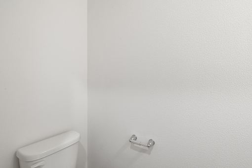 A white toilet next to a white wall.