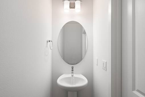 A white sink with a round mirror above it.