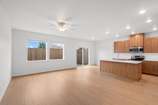A spacious kitchen and living room with wooden floors and white walls.