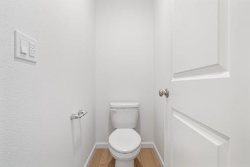 White toilet in a small bathroom with a door to the right.