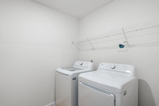 Two white front loading washing machines in a laundry room.