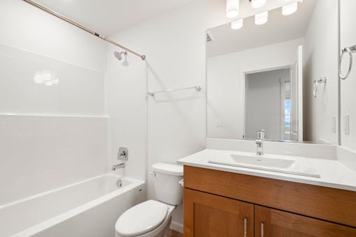 White bathroom with a toilet, sink, and mirror.
